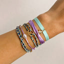 Wrist with multiple colorful bracelets on a neutral background