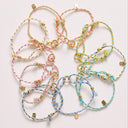 Colorful bracelets with gold charms on a light pink background