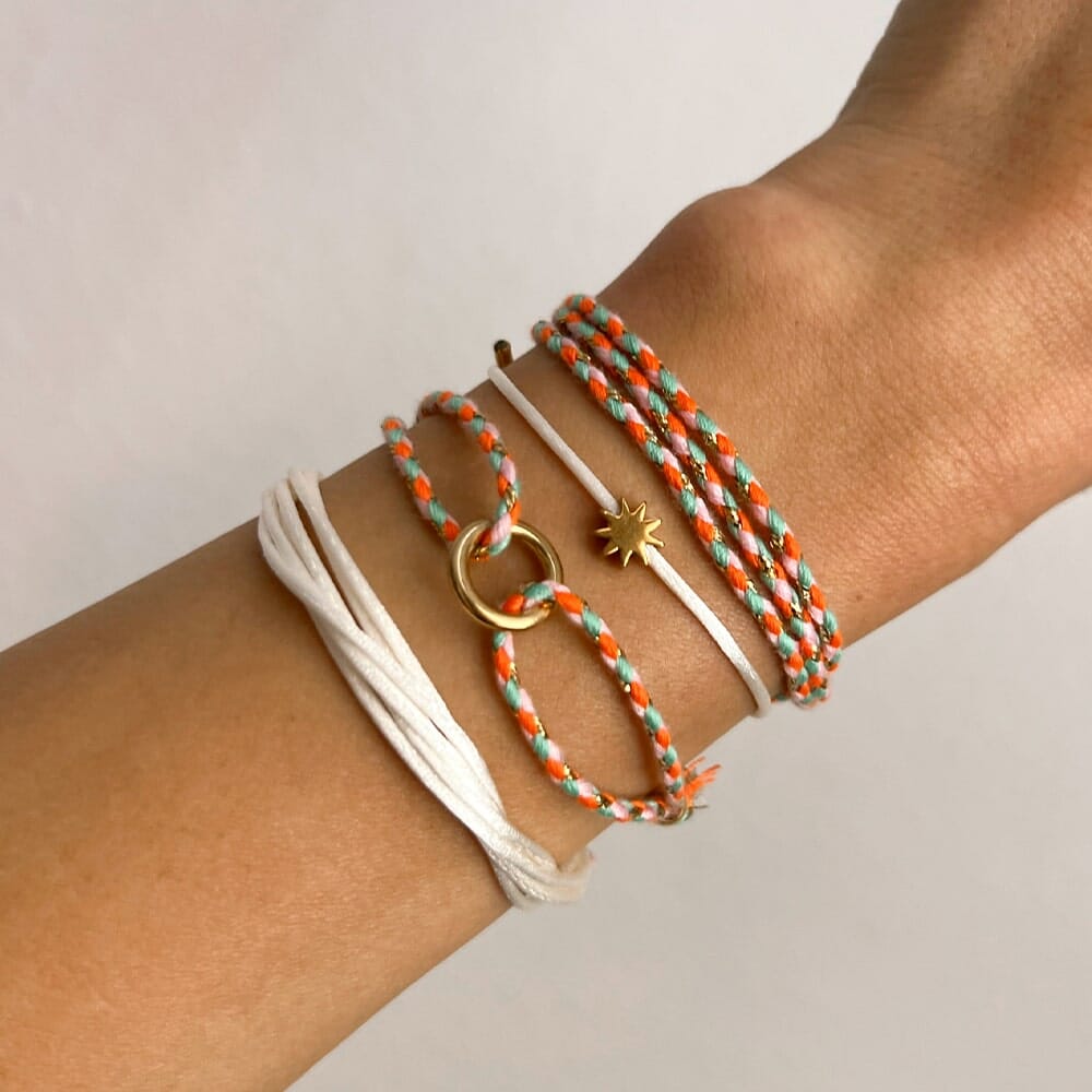 Wrist with multiple bracelets on a plain background
