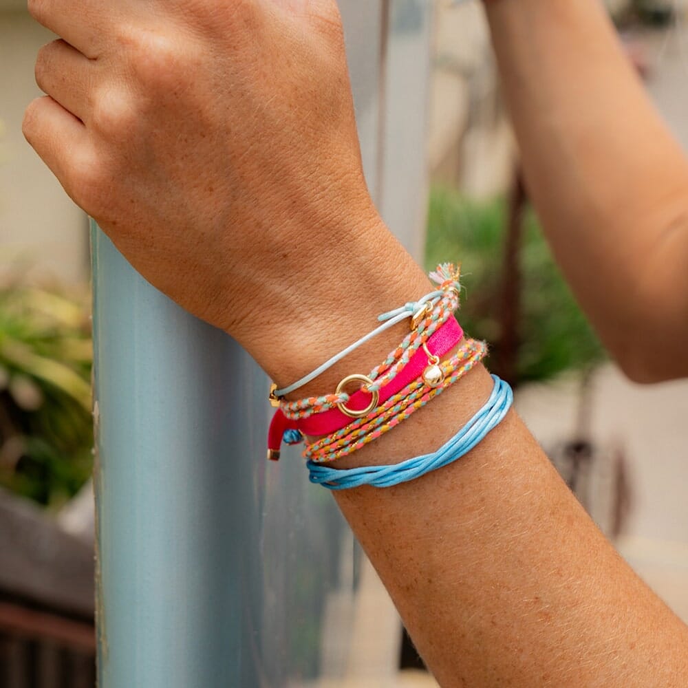 Close-up of a wrist wearing colorful bracelets with a blurred background