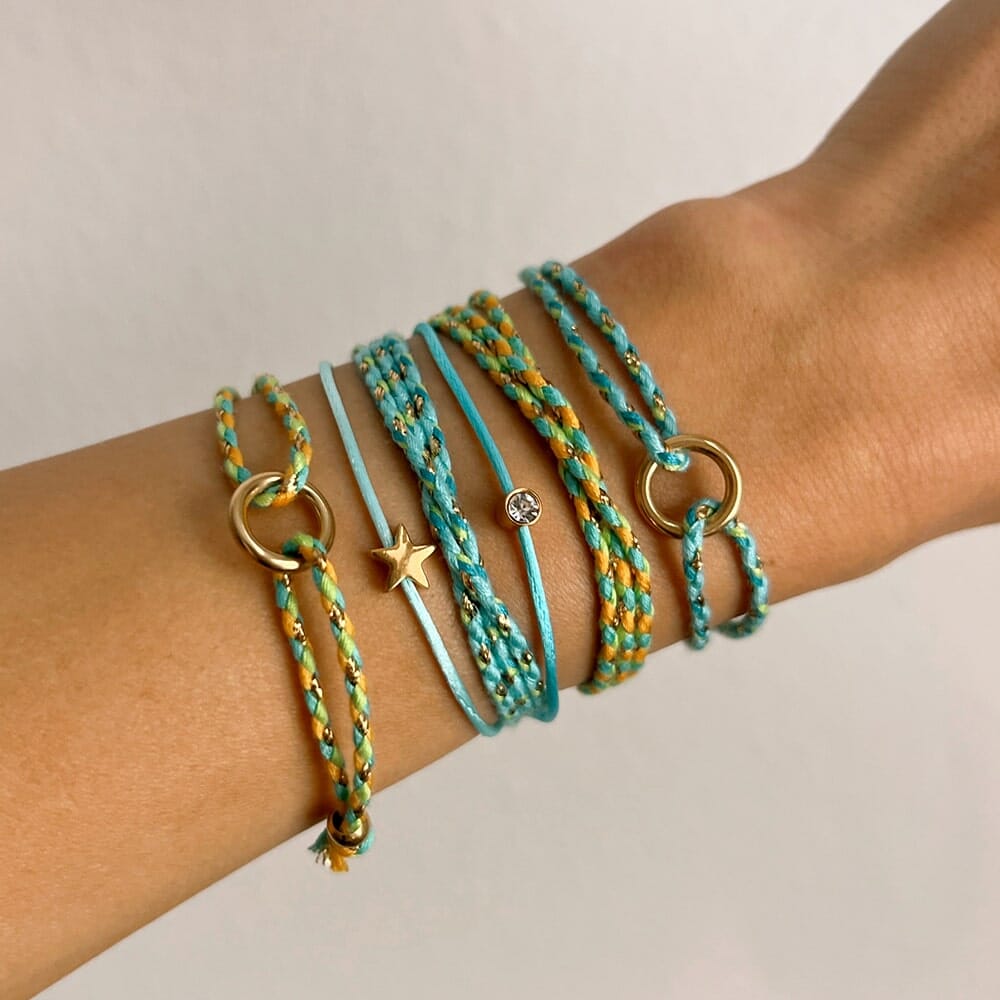 Wrist with multiple turquoise and gold bracelets on a neutral background