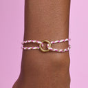 Bracelet with pink and gold design on a wrist against a pink background