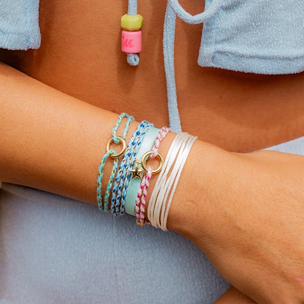 Close-up of a wrist wearing multiple colorful bracelets on a neutral background