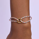 Bracelet with a gold clasp on a wrist against a light purple background