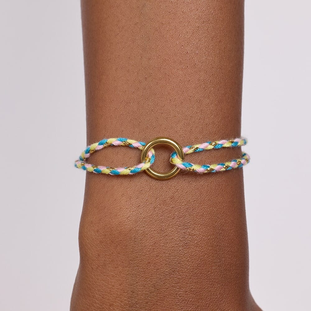 Bracelet with braided design and metal clasp on wrist against a neutral background