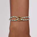 Bracelet with braided design and metal clasp on wrist against a neutral background
