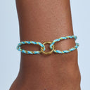 Bracelet with blue and gold design on a wrist against a light blue background