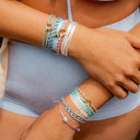 Close-up of a person's wrist with multiple colorful bracelets on a blurred background