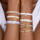 Close-up of a person's wrist wearing multiple delicate bracelets with various designs.